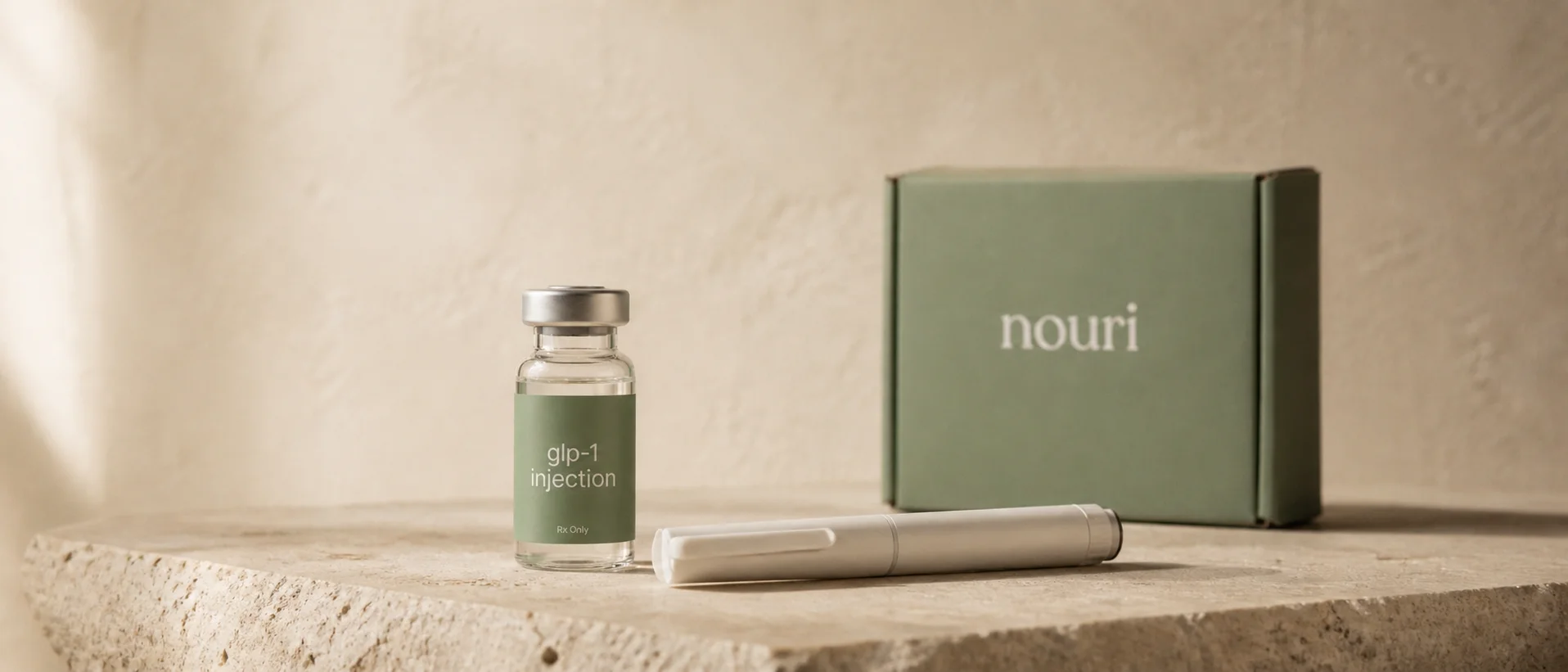 Nouri's compounded medication, dosing pen, and delivery box arranged on stone.